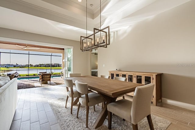 dining room with a sunroom, baseboards, wood tiled floor, a tray ceiling, and crown molding