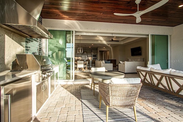 view of patio with area for grilling, ceiling fan, an outdoor living space, and an outdoor kitchen