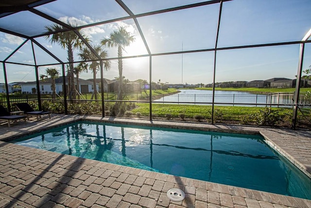 outdoor pool with a patio, a water view, a lanai, and fence