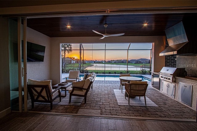 view of patio featuring a lanai, a grill, an outdoor pool, and an outdoor kitchen