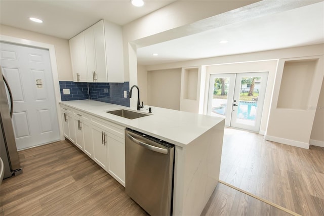 kitchen featuring tasteful backsplash, light wood-style flooring, appliances with stainless steel finishes, french doors, and a sink