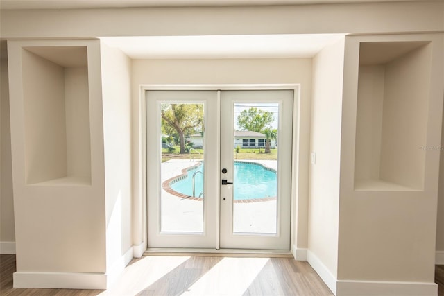 entryway featuring french doors, baseboards, and wood finished floors