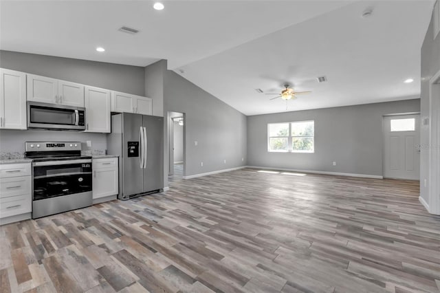 kitchen with white cabinets, light wood finished floors, appliances with stainless steel finishes, and open floor plan