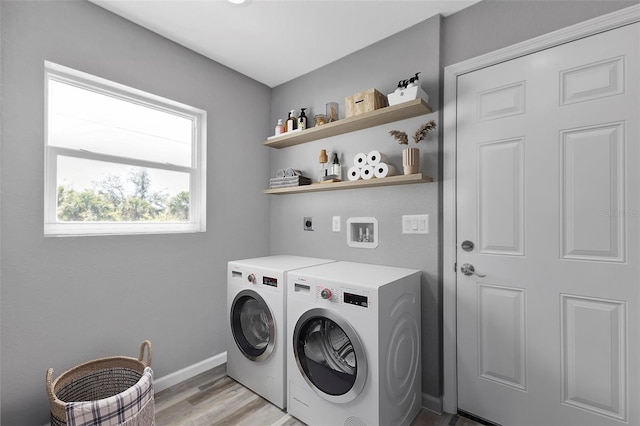 washroom featuring laundry area, light wood finished floors, washing machine and dryer, and baseboards