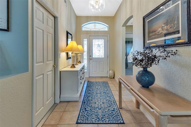 foyer entrance featuring an inviting chandelier, visible vents, arched walkways, and light tile patterned flooring