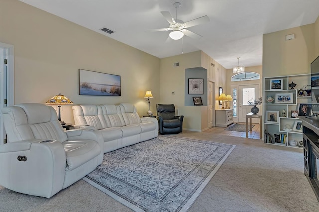 living room featuring ceiling fan with notable chandelier, visible vents, and light colored carpet