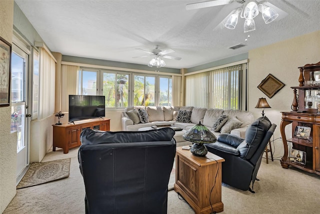 living room with a textured ceiling, a textured wall, light carpet, visible vents, and a ceiling fan