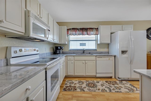 kitchen with light stone counters, white appliances, a sink, and white cabinetry