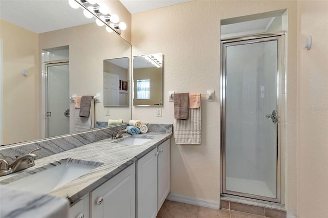 bathroom with tile patterned flooring, a sink, and a shower stall