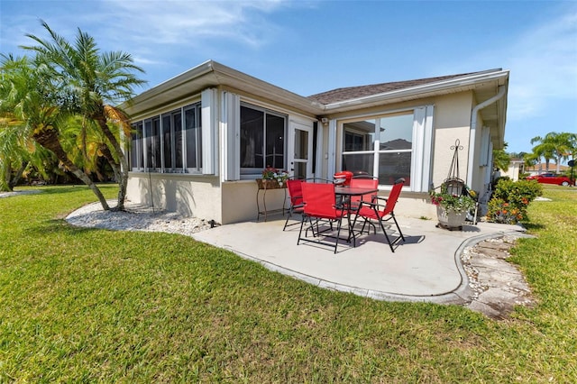 rear view of property featuring a lawn, a patio area, a sunroom, and stucco siding