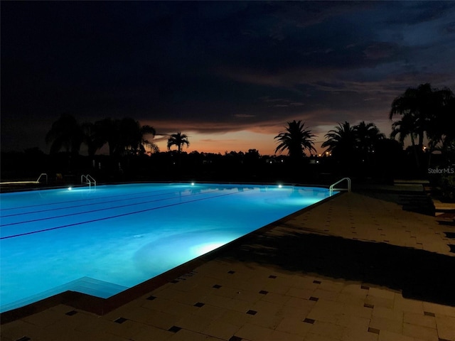 pool at dusk featuring a community pool