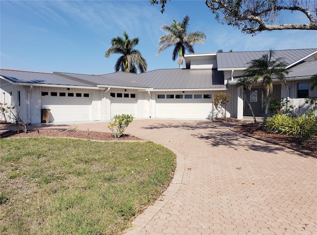 view of front of home featuring decorative driveway, metal roof, an attached garage, and a standing seam roof