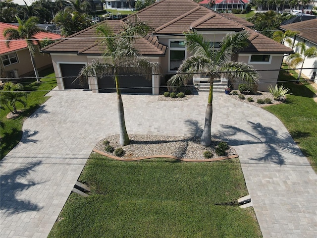 mediterranean / spanish home featuring an attached garage, stucco siding, decorative driveway, and a tiled roof