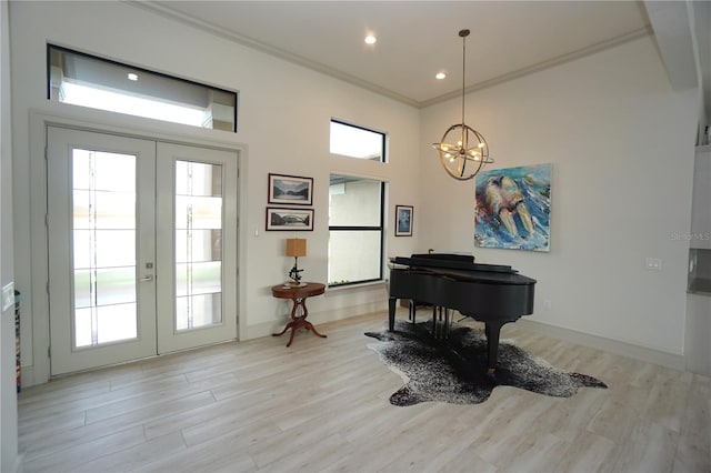 living area featuring light wood-style flooring, ornamental molding, baseboards, and french doors