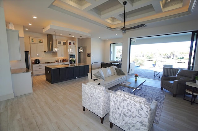 living room with coffered ceiling, a high ceiling, light wood-style floors, beam ceiling, and recessed lighting