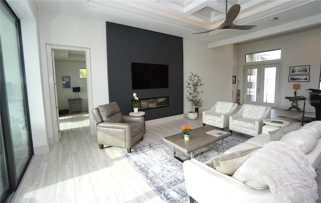 living area with light wood-style flooring, coffered ceiling, visible vents, a ceiling fan, and french doors