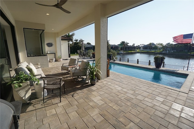 view of patio / terrace with a water view, a ceiling fan, and an outdoor pool