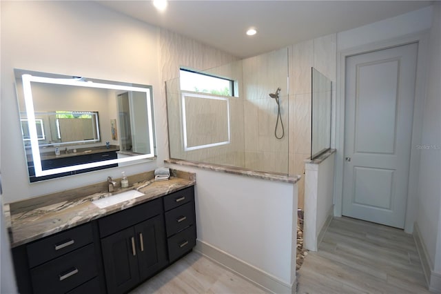 full bath featuring recessed lighting, wood finished floors, vanity, and walk in shower