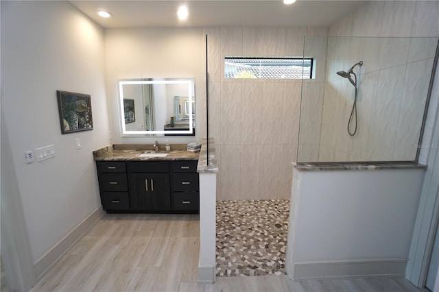 full bath with baseboards, wood finished floors, vanity, a walk in shower, and recessed lighting