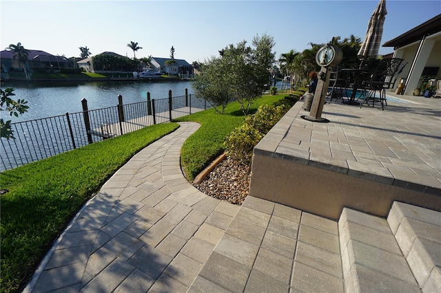 view of property's community featuring a patio, a water view, fence, and a residential view