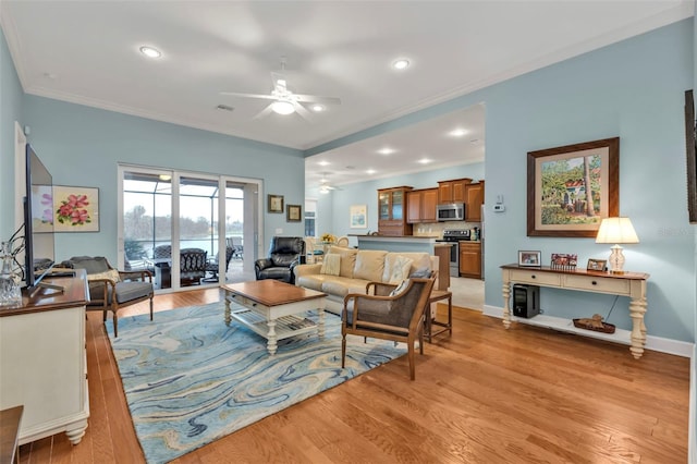 living room with baseboards, a ceiling fan, light wood-style flooring, and crown molding