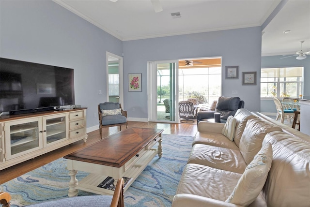 living room featuring ornamental molding, visible vents, ceiling fan, and wood finished floors