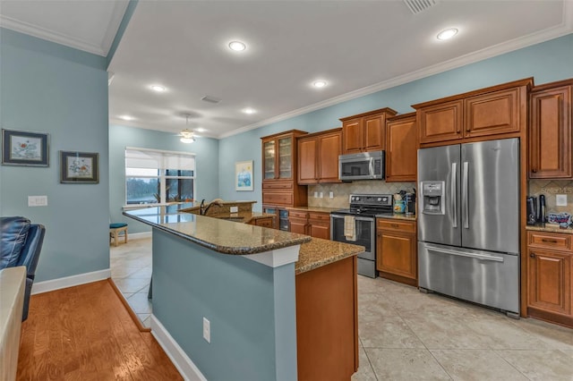 kitchen featuring stainless steel appliances, brown cabinets, and ornamental molding