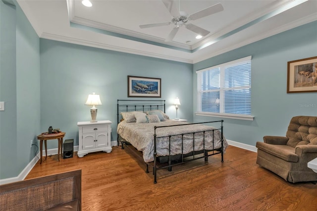 bedroom with recessed lighting, wood finished floors, baseboards, ornamental molding, and a raised ceiling