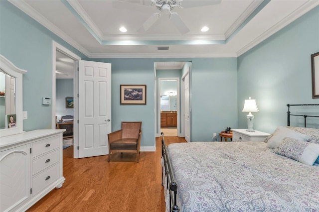 bedroom with a raised ceiling, visible vents, crown molding, and light wood-style flooring