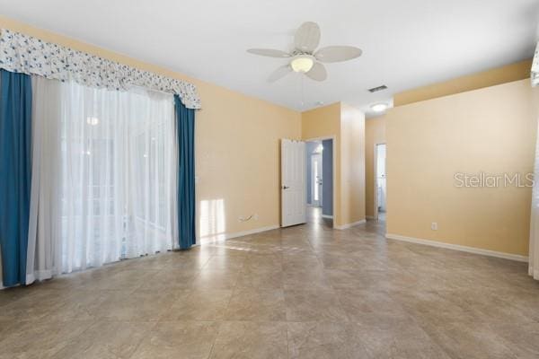 spare room with visible vents, ceiling fan, and baseboards