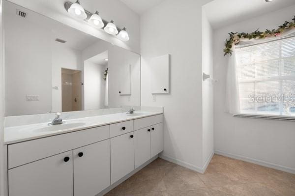 full bath featuring double vanity, a sink, visible vents, and baseboards