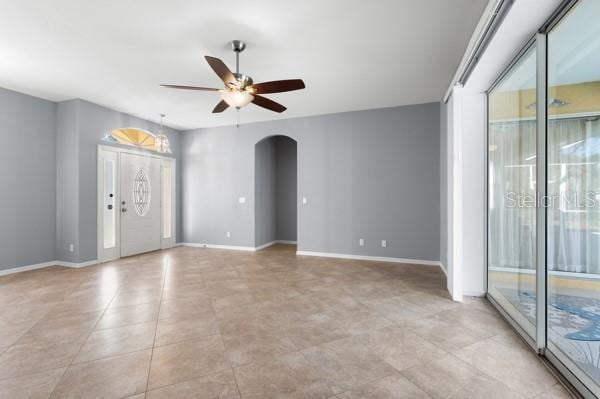 spare room with baseboards, arched walkways, and a ceiling fan