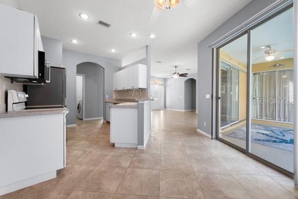 kitchen featuring arched walkways, visible vents, and white cabinetry