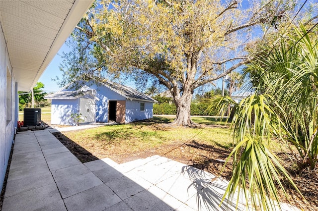 view of yard with central AC, a patio, and an outdoor structure