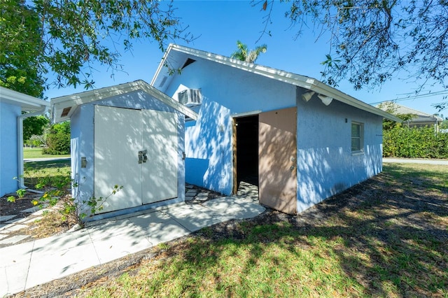 exterior space with a storage shed, stucco siding, and an outdoor structure