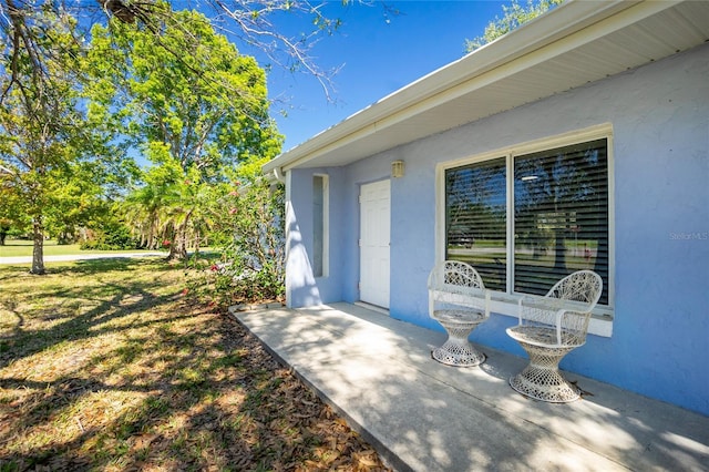 doorway to property featuring a lawn and stucco siding