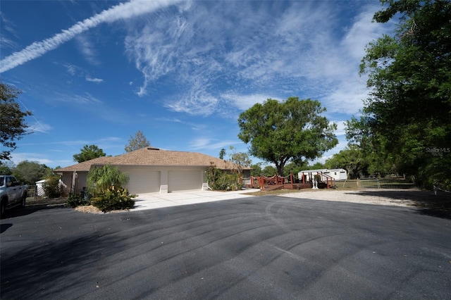 view of front of home with a garage, concrete driveway, and fence