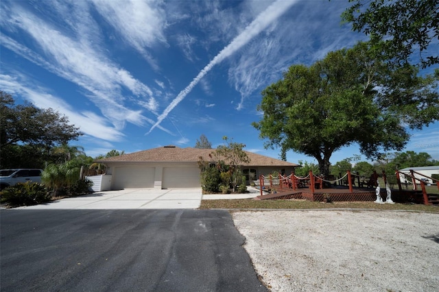 ranch-style home featuring an attached garage, a playground, concrete driveway, and stucco siding