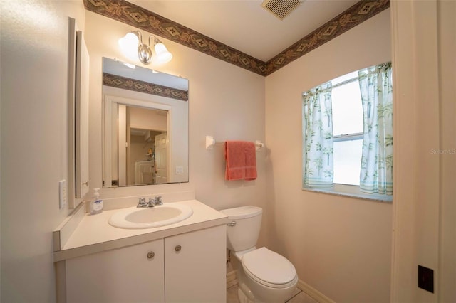 bathroom featuring toilet, vanity, visible vents, and baseboards