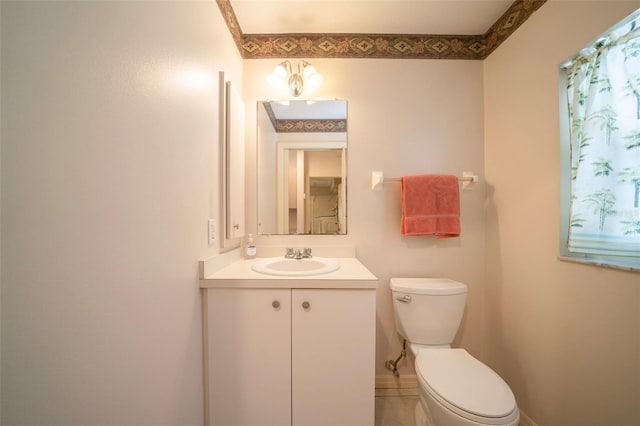 half bathroom with toilet, baseboards, and vanity