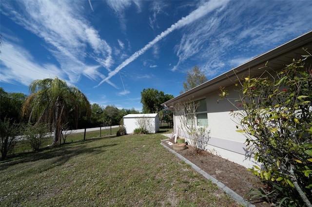 view of yard featuring an outdoor structure, a storage shed, and fence