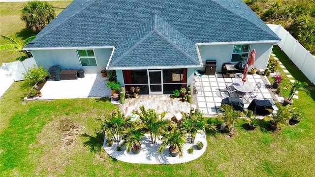 back of house with a fenced backyard, a sunroom, a yard, roof with shingles, and a patio area