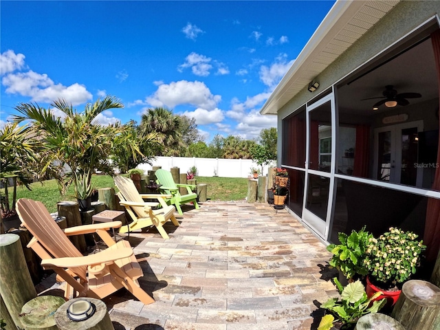 wooden terrace with a ceiling fan, a sunroom, fence, and a patio
