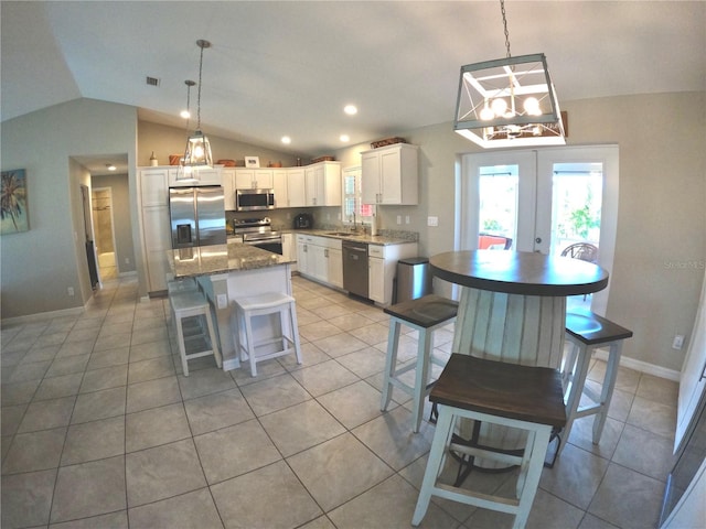 kitchen featuring lofted ceiling, stainless steel appliances, a kitchen island, white cabinets, and french doors