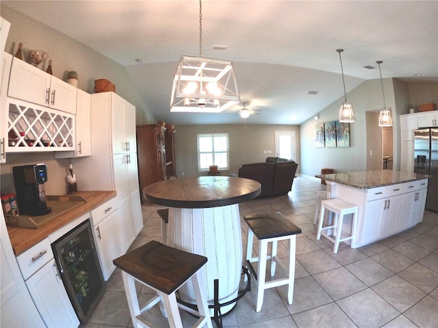 kitchen with a kitchen island, a breakfast bar area, white cabinets, and stainless steel fridge with ice dispenser