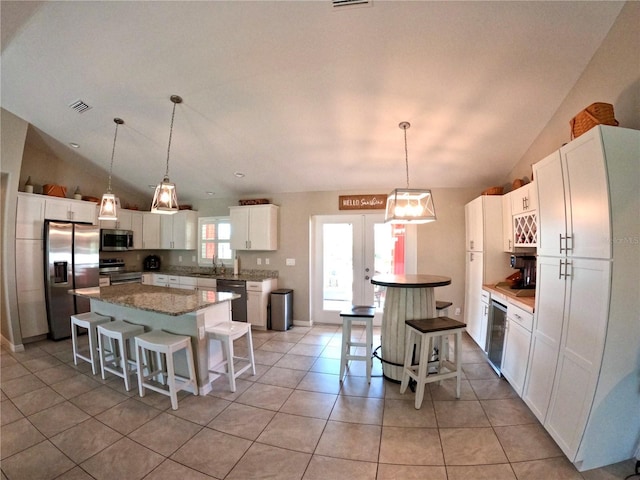 kitchen featuring stainless steel appliances, a kitchen island, visible vents, a kitchen breakfast bar, and french doors