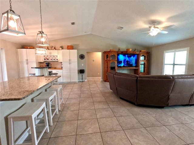 living area featuring lofted ceiling, visible vents, a ceiling fan, and light tile patterned flooring