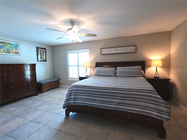 bedroom with ceiling fan, baseboards, a textured ceiling, and tile patterned floors