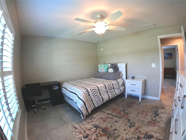 tiled bedroom with baseboards and a ceiling fan