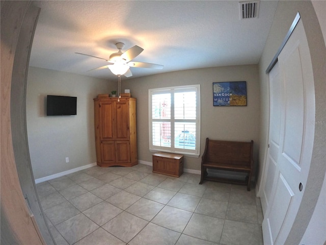 unfurnished room featuring light tile patterned floors, visible vents, baseboards, a ceiling fan, and a textured ceiling